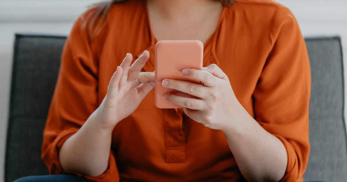Close-up on the torso of a woman holding a smartphone.