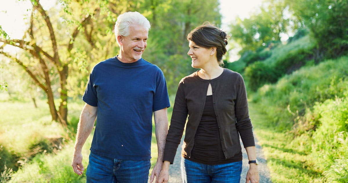 A middle-aged couple walks down a trail.