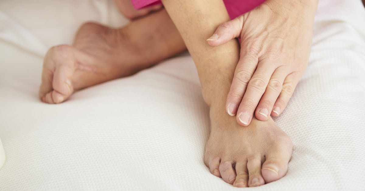 a pair of feet in bed, with a hand rubbing one of them