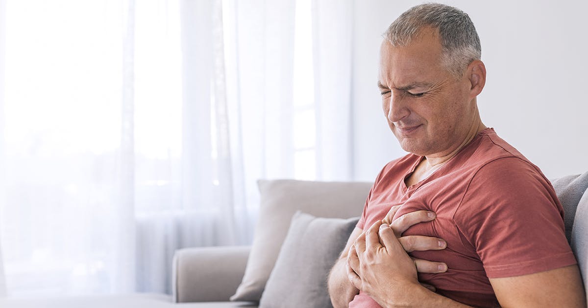  A man with chest pain grimaces and holds his hands to his chest.