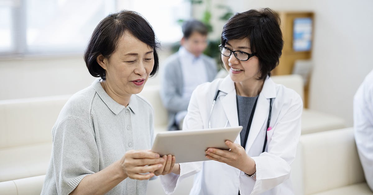  A doctor and woman look at a tablet together. 