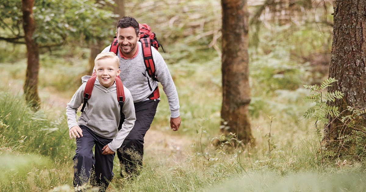 Man and boy with backpacks on a hiking trail.