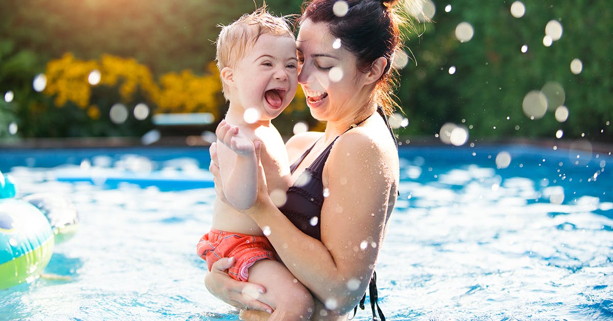 A woman holds a child in a pool. 