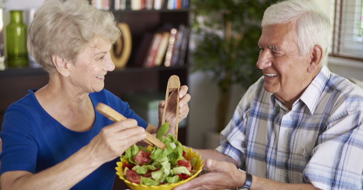 An older couple sharing a small bowl of salad.