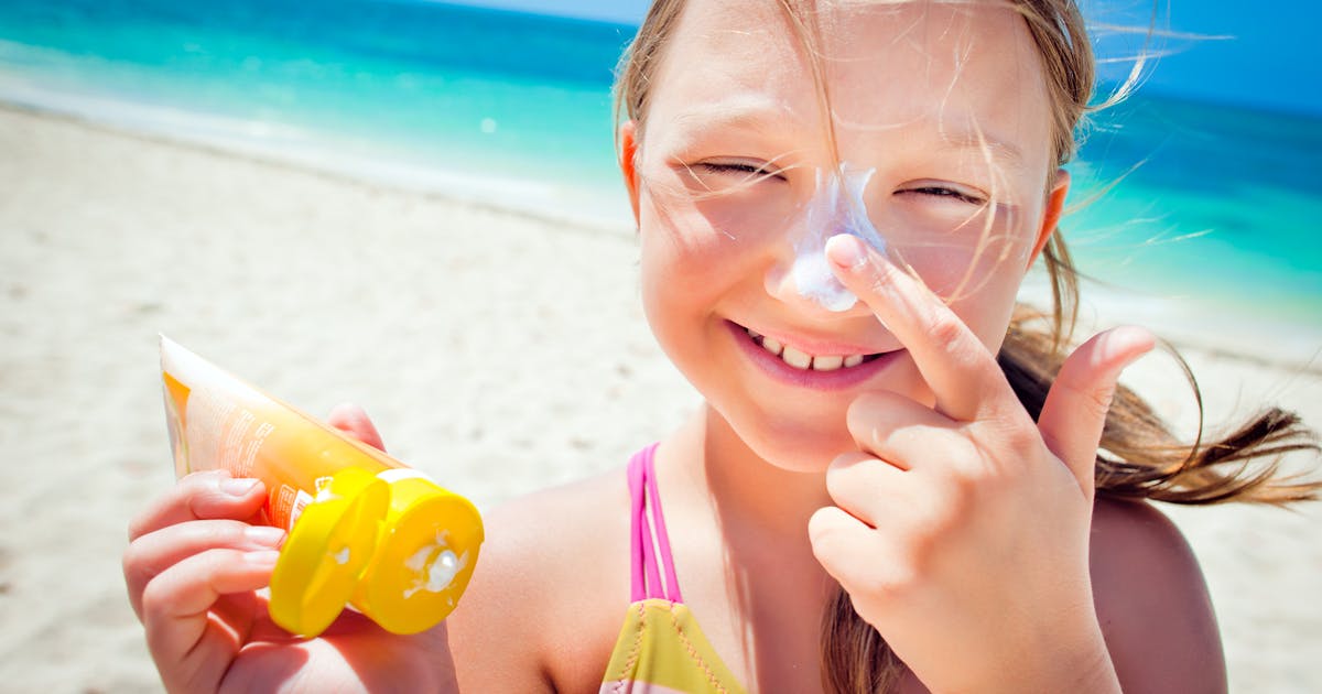 Young girl placing sunscreen on her nose.