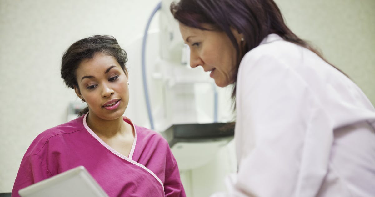 A doctor talks to a robed patient after her mammogram