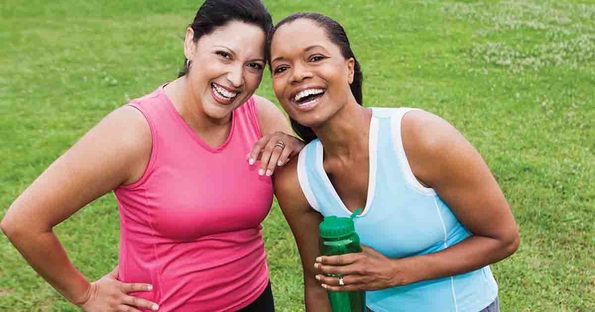 Two smiling women outdoors in tank tops.