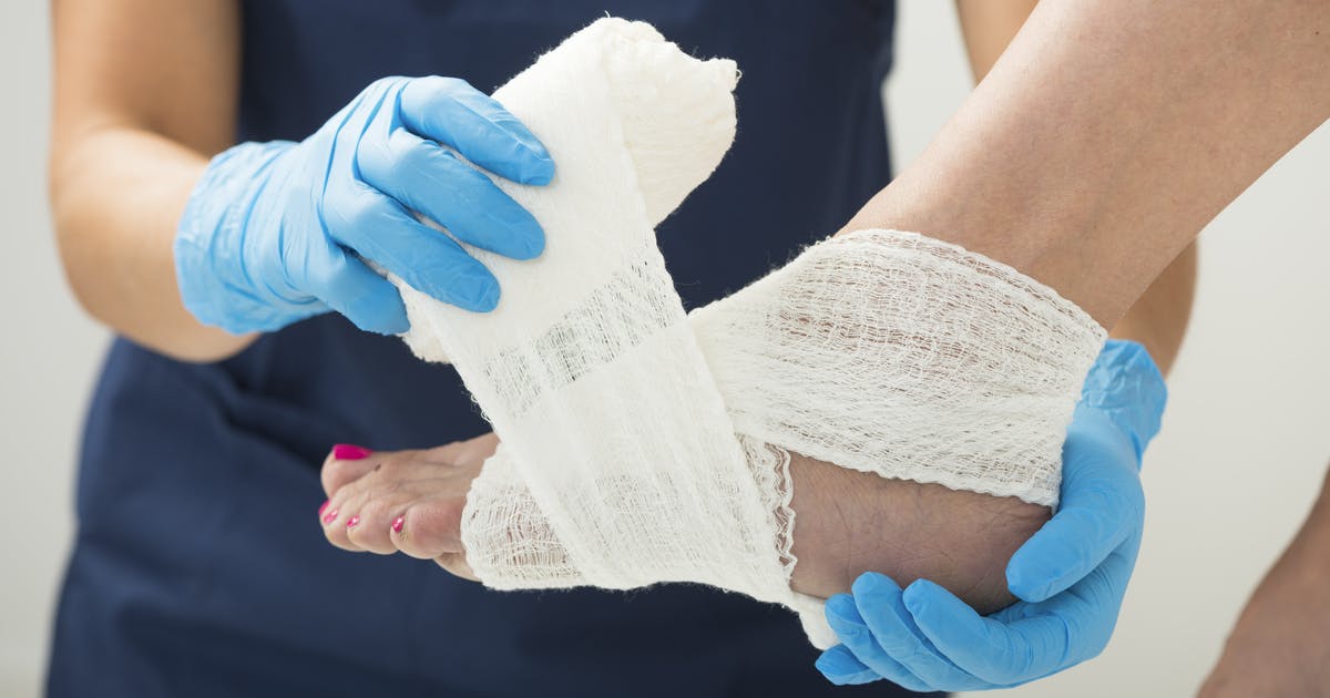 A nurse wraps a gauze bandage around a patient's foot