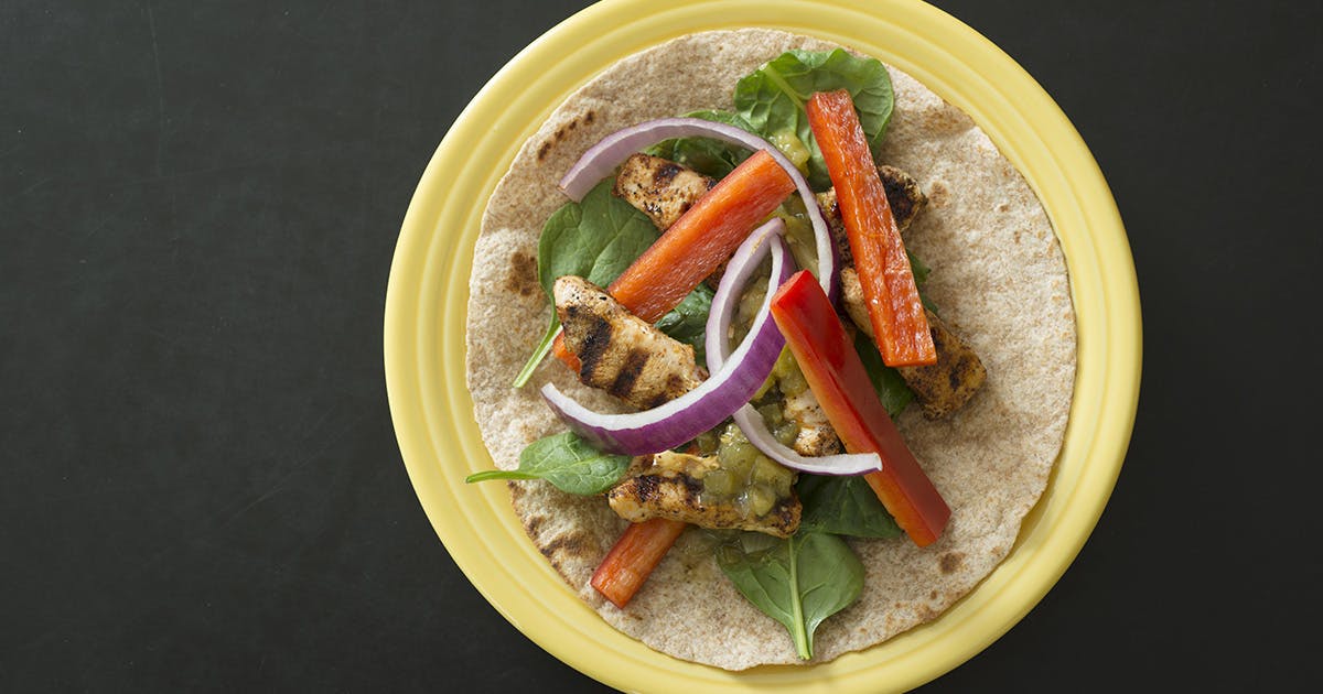 A turkey fajita with baby spinach and red peppers. 