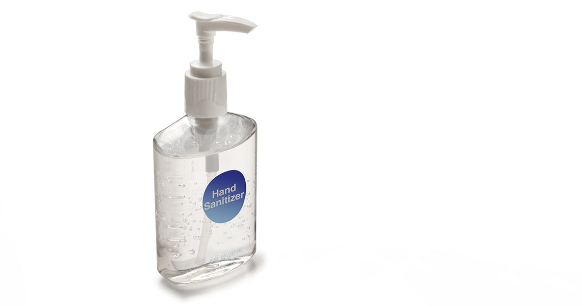 A clear pump bottle filled with clear hand sanitizer, little bubbles suspended inside it, on a white background.
