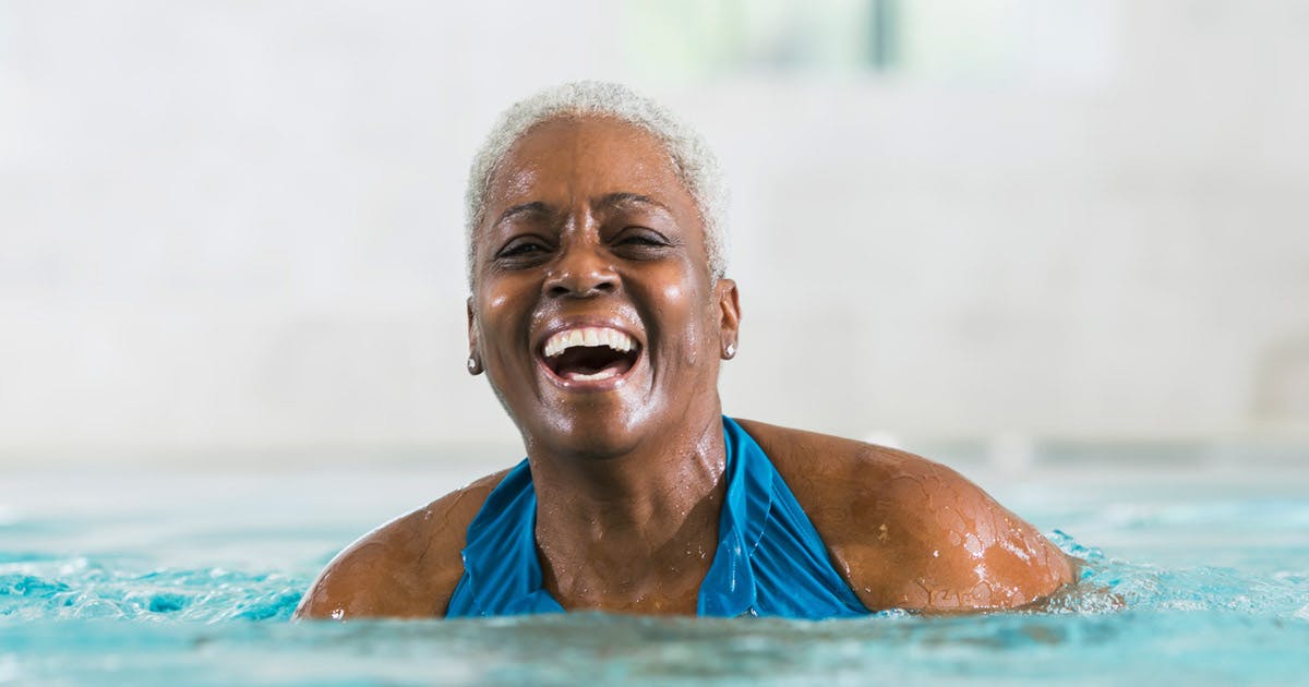 A laughing woman standing in a pool. 