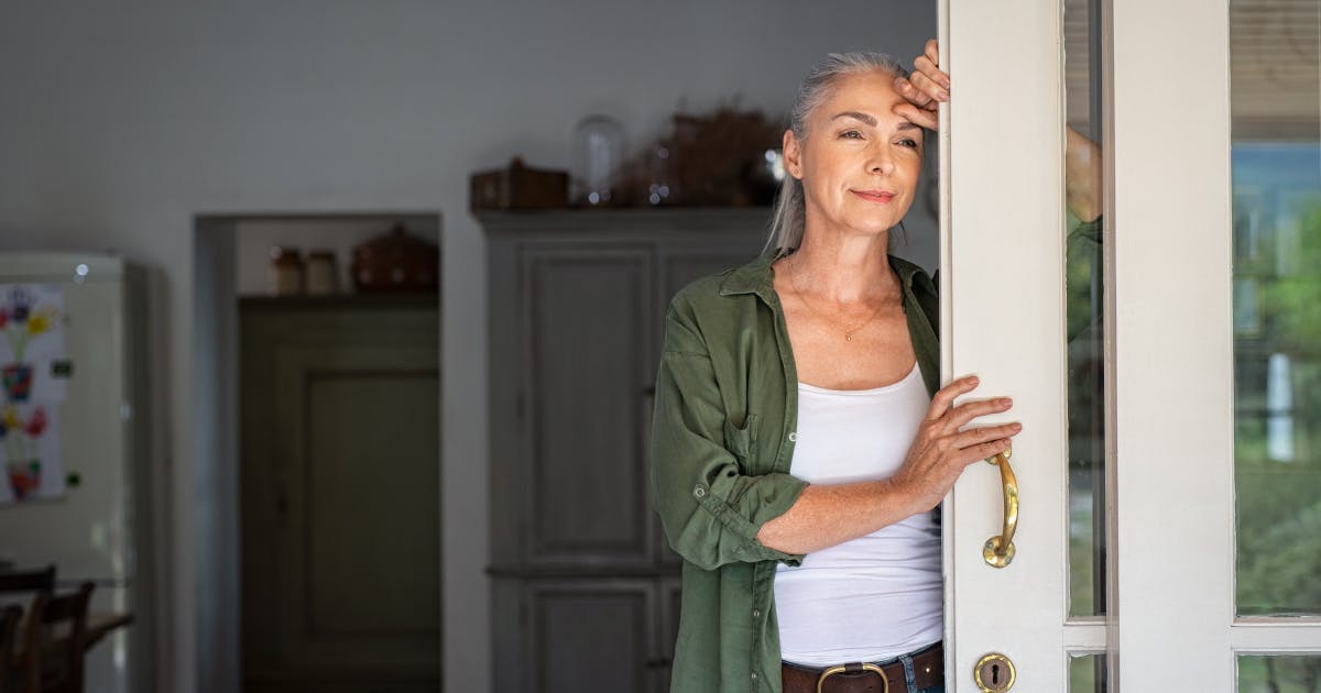  An older woman looks pensively out her sliding door