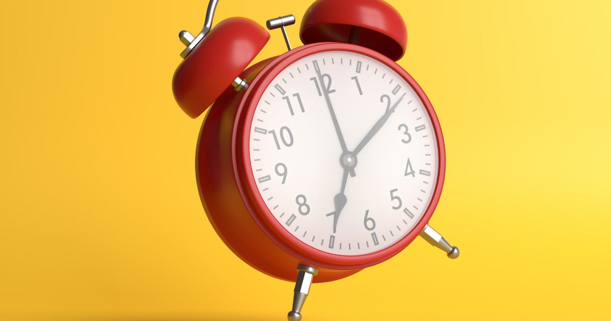 A red analog alarm clock on yellow background.