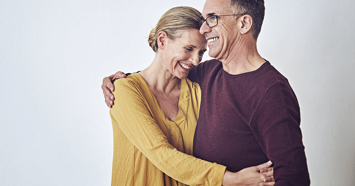 A middle-aged man and woman hug. 