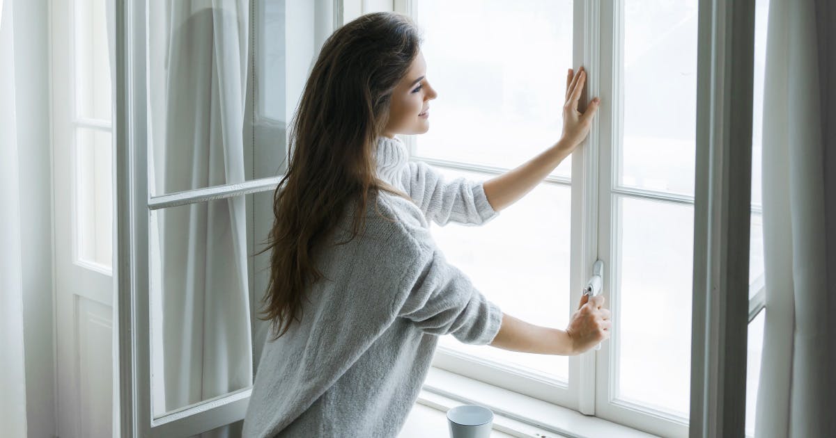 A woman opens a window.