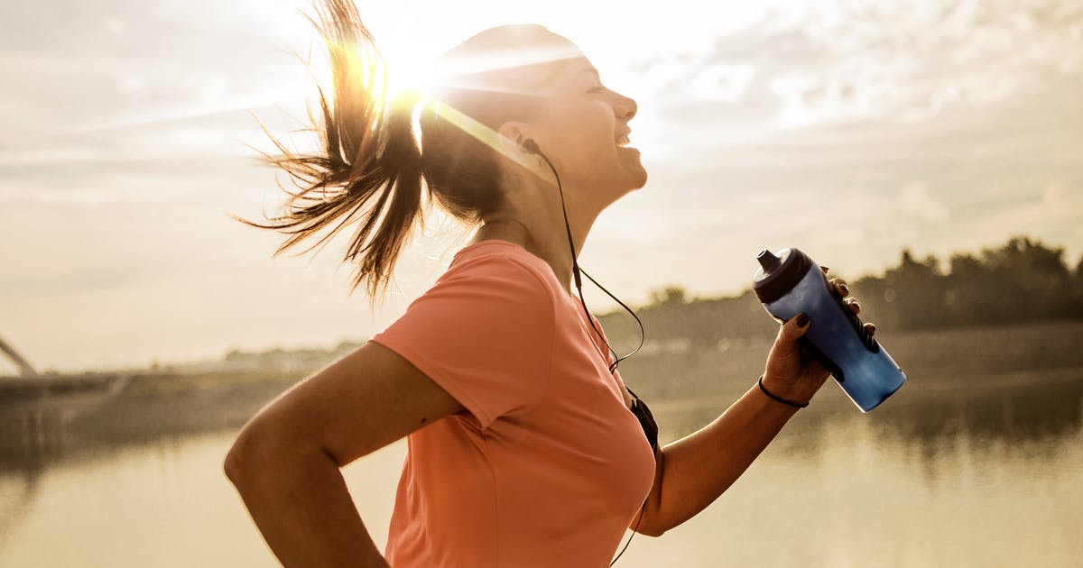 A woman runs while holding a water bottle.