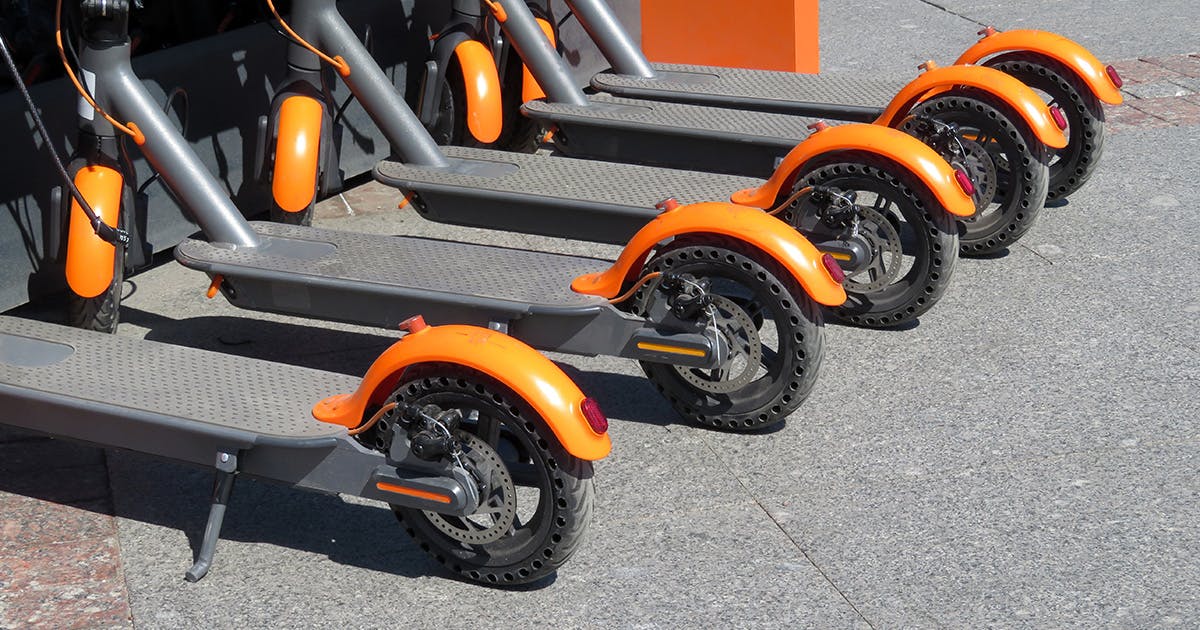 A row of orange and gray e-scooters.