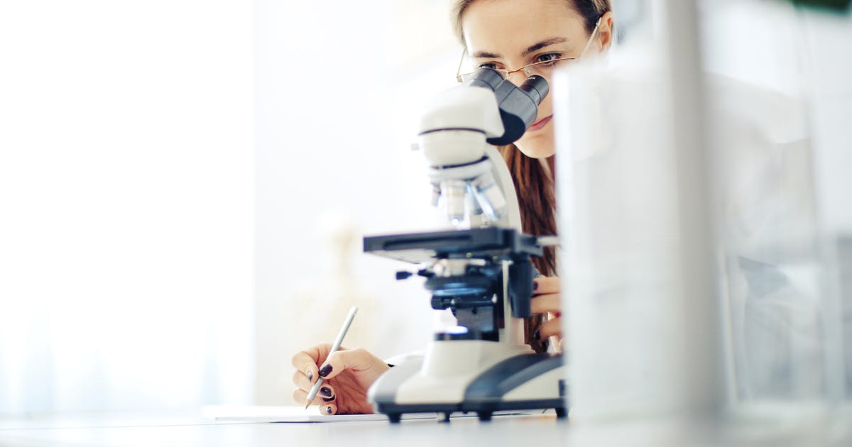A woman looks into a microscope