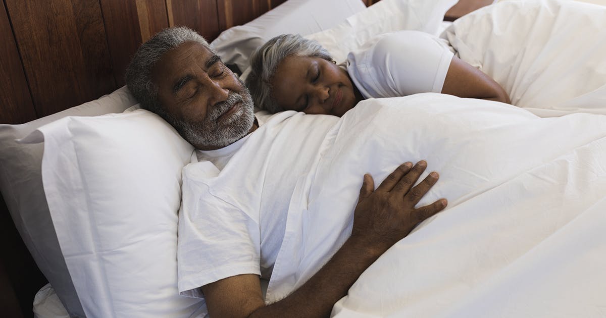 A man and woman sleeping in a bed.