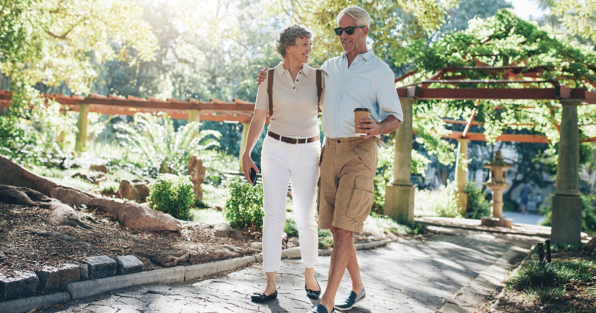 A middle-aged man and woman walking arm in arm on a sunny day. 