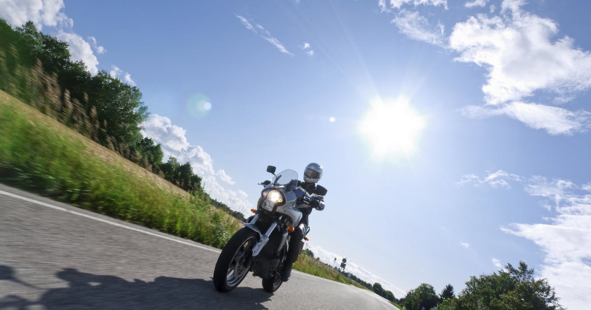 A person riding a motorcycle on a country road on a sunny day.
