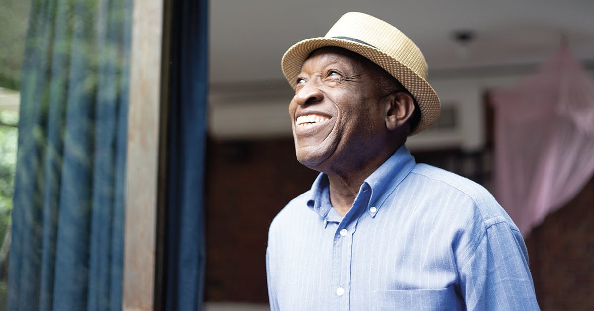 A smiling black man in a hat. 