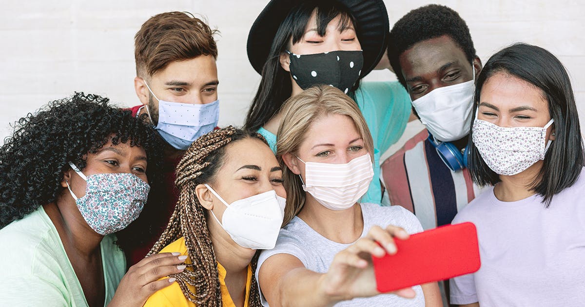 A group of teens in face masks pose for a selfie.